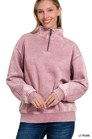 Woman in a light rose pink acid wash fleece quarter zip sweatshirt with ribbed cuffs.