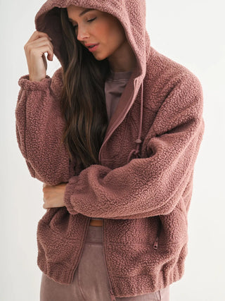 Woman wearing fleece hoodie with hood up, showing soft textured fabric.