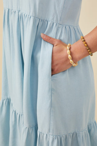 Close-up of the soft chambray fabric and hidden side pocket detail on a tiered puff-sleeve midi dress — comfortable and functional design.