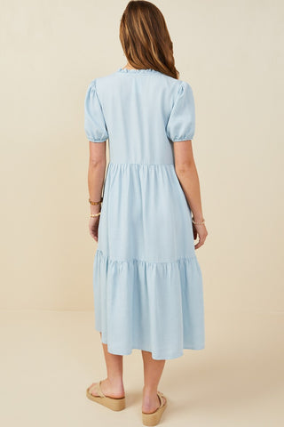 Back view of a lightweight chambray midi dress with short puff sleeves and a flowy tiered silhouette — perfect for brunches, showers, and sunny days.
