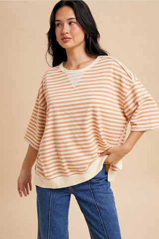 Model wearing an apricot and cream striped French terry short sleeve top styled with blue jeans.