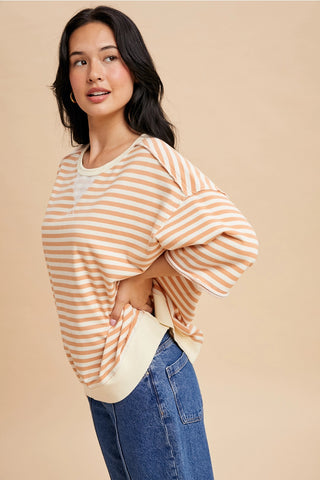Side view of apricot and cream striped french terry short sleeve top with dropped shoulders and casual relaxed style.
