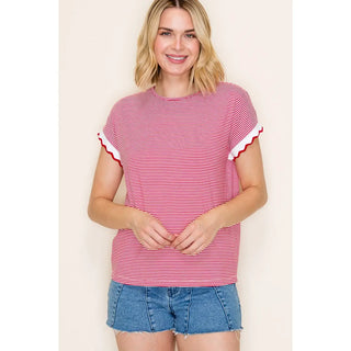 Woman wearing a red and white striped shirt with blue shorts on a beige background