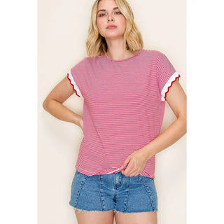 Woman wearing a red and white striped shirt with blue shorts on a plain background