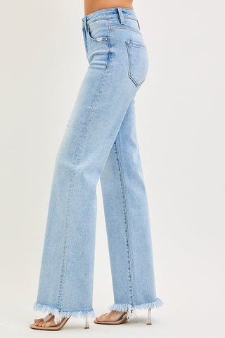 Side view of high rise straight jeans with soft fading and raw hem detail.