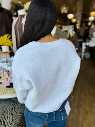 Back view of a woman wearing a light grey sweatshirt showing the back has no writing.