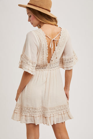 Back view of the same lace-trim mini dress style showing the open back with tie detail and ruffled hem — note: color shown is not available; only sold in mauve rose.