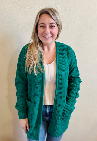 Model wearing the forest waffle knit cardigan with pockets styled over a neutral ribbed tank and denim