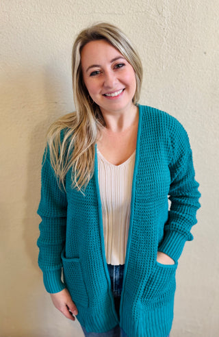 Model wearing the light teal waffle knit open front cardigan with pockets styled over a neutral ribbed tank and denim