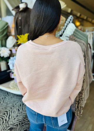Back view of the woman wearing a light pink sweatshirt showing there is no writing on the back of the sweatshirt.