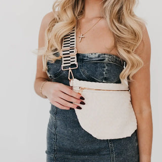 Model wearing the Westlyn bum bag in ivory with a bold black and ivory striped strap and gold zipper — styled over a strapless denim dress.