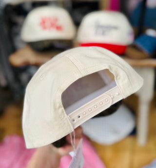 Back view of the tan trucker hat featuring an adjustable snapback closure in matching tan, with a glimpse of the curved leopard print brim.