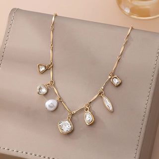 Close-up of mixed charm collection featuring twisted nugget, heart crystal, faceted crystal, pearl and teardrop charms on gold necklace