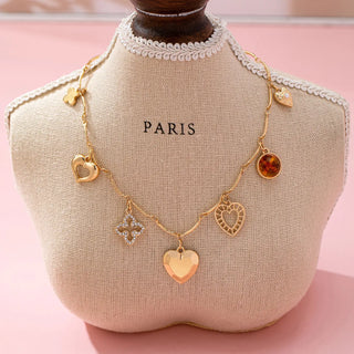 Gold bar-link chain necklace with friendship-themed charms - clover for luck and hearts for love