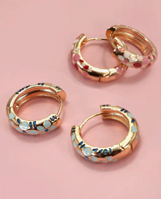 Close-up of gold plated enamel flower huggie hoops showing hinge back closure detail