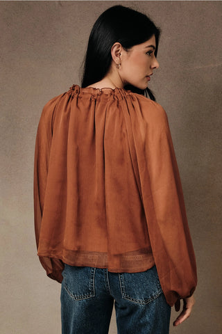 Back view of rust sheer chiffon peasant blouse showing voluminous long sleeves and ruffled gathered neckline