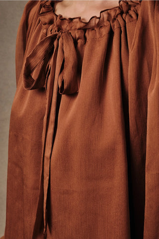 Close-up of ruffled tie-front collar and crinkle chiffon fabric texture on rust boho peasant blouse