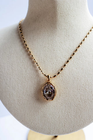 Closeup of Eva Waterproof Gold Necklace pendant — faceted oval crystal stone set in a gold bezel on a dainty gold link chain, stainless steel tarnish resistant