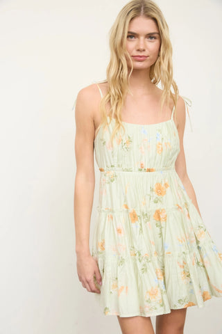 Woman wearing a light green floral dress, showing the mini length.