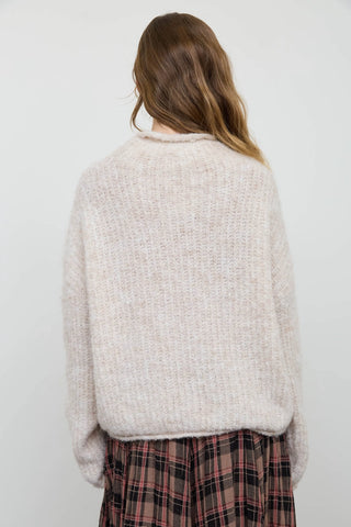 Back view of women's cream fuzzy knit pullover sweater showing drop shoulder fit and relaxed silhouette, styled with plaid skirt