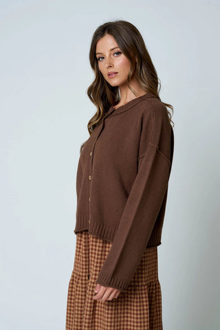 Side view of women's relaxed fit brown knit cardigan with exposed seam detail, button down front, and long drop shoulder sleeves