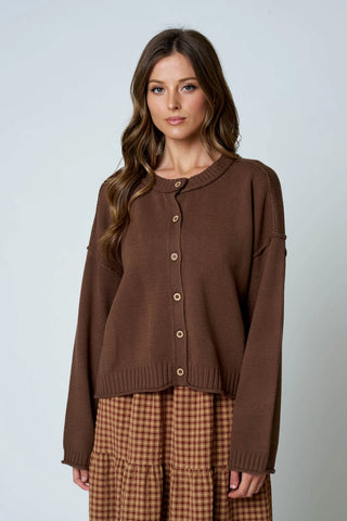 Women's brown raw edge exposed seam button down knit cardigan with crew neckline and drop shoulder, styled with plaid midi skirt