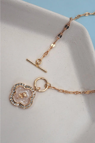 Close-up of rhinestone-studded rose flower charm and gold toggle clasp on paperclip chain necklace