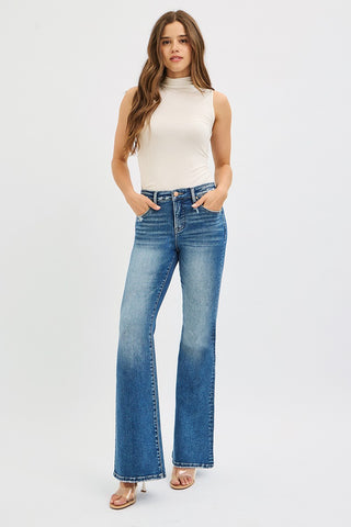 Model wearing Risen Tummy Control High Rise Flare Jeans in dark wash with white sleeveless mock neck top – full length outfit view