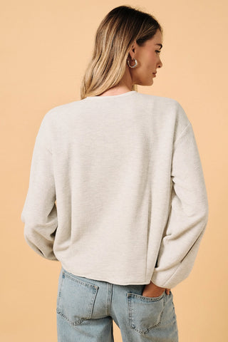 Back view of Round Neck Barrel Hem Knit Jacket in ash grey — textured knit fabric with barrel hem waist and long sleeves, styled with light wash denim