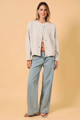 Full length front view of Round Neck Barrel Hem Knit Jacket in ash grey — model wearing open knit button-up jacket over crop top with wide-leg jeans and sandals