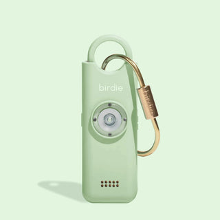 She's Birdie 3.0 personal safety alarm in Matcha with brass keychain and front-facing light.