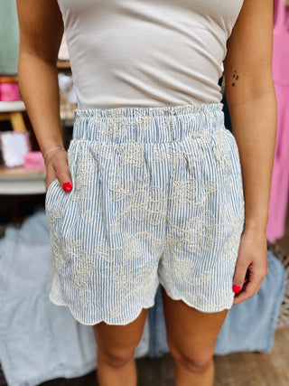 Close-up of textured stripe fabric and delicate embroidery detail on scallop hem shorts
