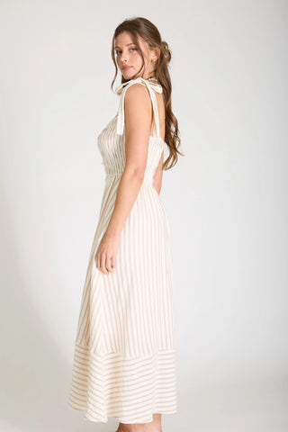 Side view of woman wearing a striped midi length dress with tied strap shoulder ties.