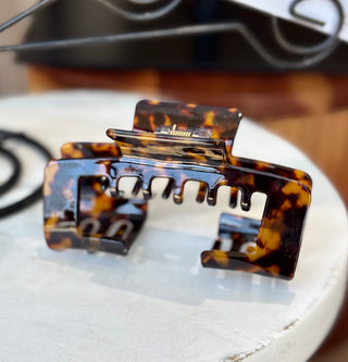 Large tortoiseshell colored hair claw clip featuring a unique design with missing space to wear your hair up with a trucker or baseball hat.